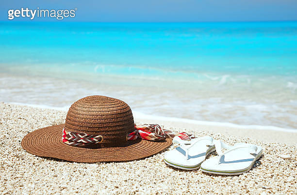 Hat and flip flops on a beach (510533993) - 게티이미지뱅크