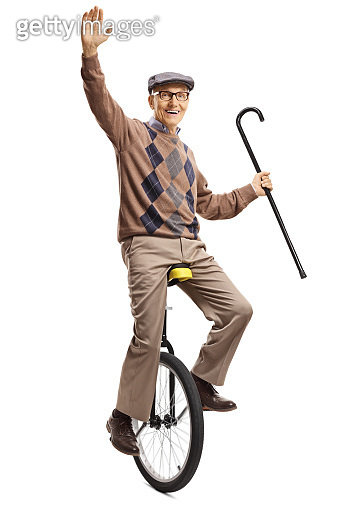 Senior man riding a unicycle and holding a walking cane (1158071433 ...