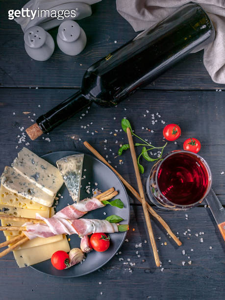 Still life glass and bottle of red wine, snacks, jamon, cheese, cherry ...