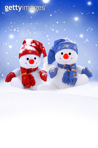 Two little snowmen the girl and the boy in caps and scarfs on snow in ...