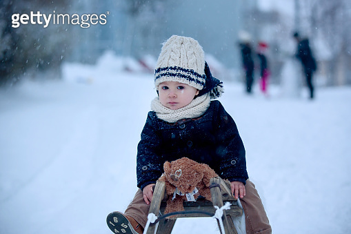 Baby playing with teddy in the snow, winter time. Little toddler boy in ...