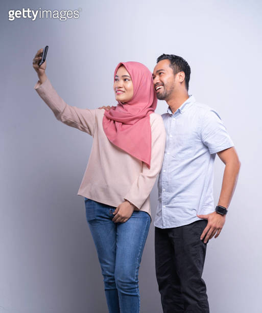 Young Asian Malay couple taking a selfie together on mobile phone ...