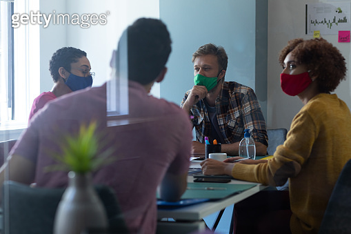 Diverse group of colleagues wearing face masks in office meeting ...