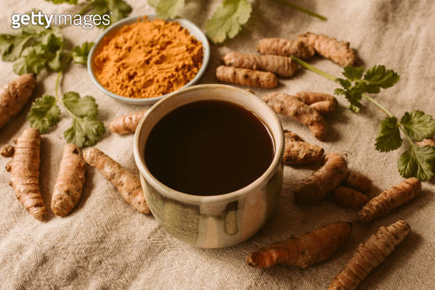 Fresh and organic turmeric root and powder with tea and coriander as ...
