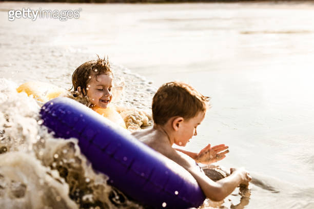 Happy little boy and his friend swimming with inflatable rings in the ...