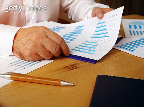 The manager is checks a report with graphs about the level of sales ...