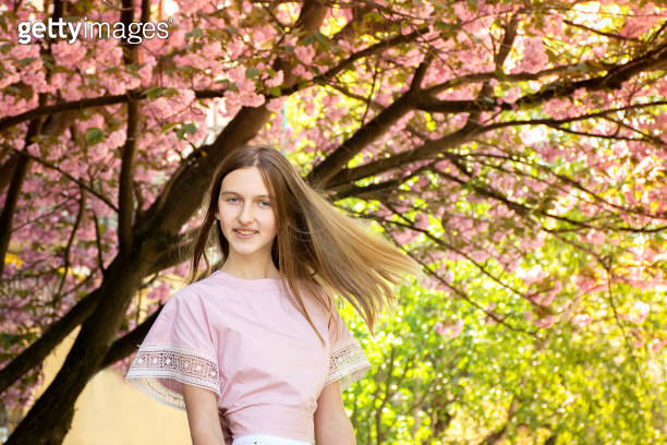 Portrait of a beautiful teenage girl in delicate sakura flowers ...