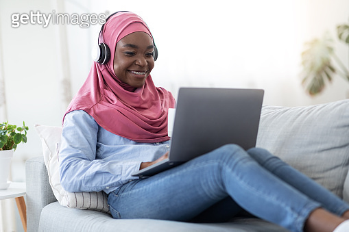 Home Pastime. Black Muslim Woman In Hijab Relaxing With Laptop And ...