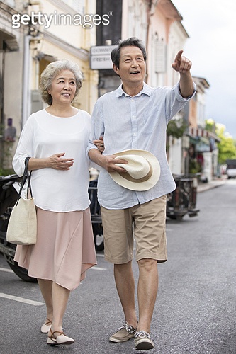 Happy senior Chinese couple walking on street (a12297385) - 게티이미지뱅크