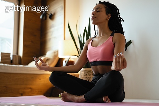 Young black woman doing yoga at home in the lotus position. (1352023270 ...