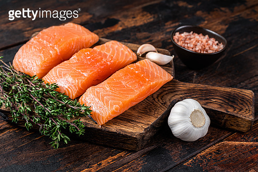 Fresh Raw salmon fish fillet steaks on wooden board with thyme. Dark ...