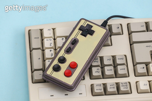 Retro gamepad on old pc keyboard. Blue background. Attributes 80s ...