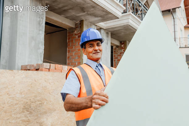 Happy constructor standing outside behind empty cardboard with copy ...