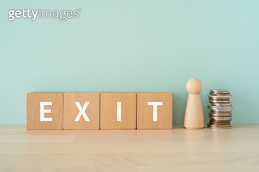 Wooden blocks with "EXIT" text of concept, a human toy, and coins ...