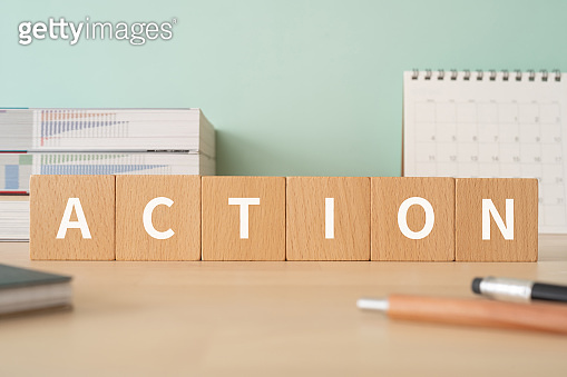 Wooden blocks with "ACTION" text of concept, pens, notebooks, and books ...