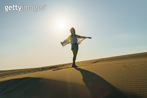 Millennial Woman standing on wavy sand dunes in desert (1391896017 ...