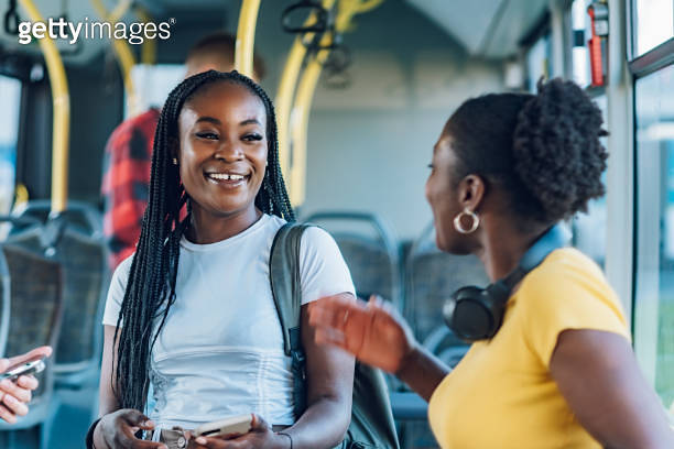 Two african american woman friends talking while riding a bus in the ...