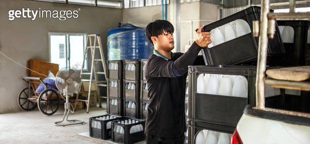 Thai Asian Workers lift white drinking water bottles in crates into the ...