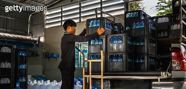 Thai Asian Workers lift Blue drinking water bottles in crates into the ...