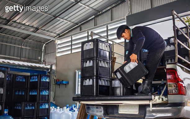 Thai Asian Workers lift white drinking water bottles in crates into the ...
