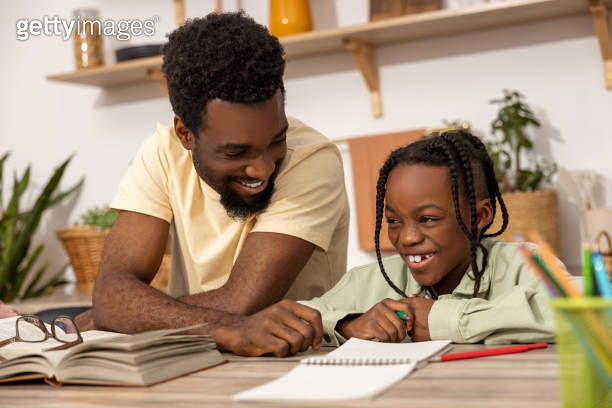 Young multiethnic father helping his daughter with her homework ...