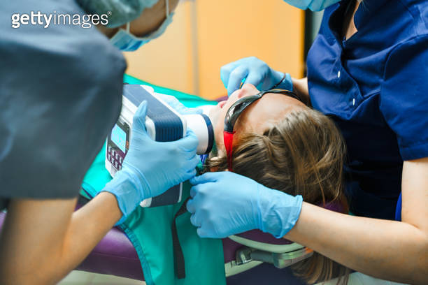 Dental portable tooth X-ray. Little scared girl sitting in chair in ...