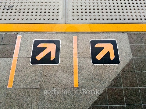 Yellow arrows sign and tactile paving for the visually impaired ...