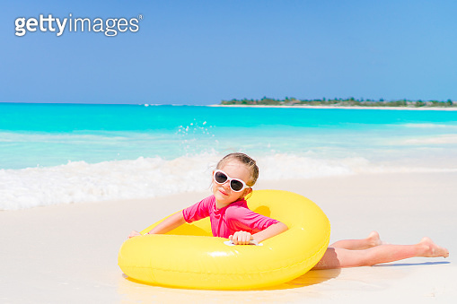 Happy little girl with inflatable rubber circle having fun on the beach ...