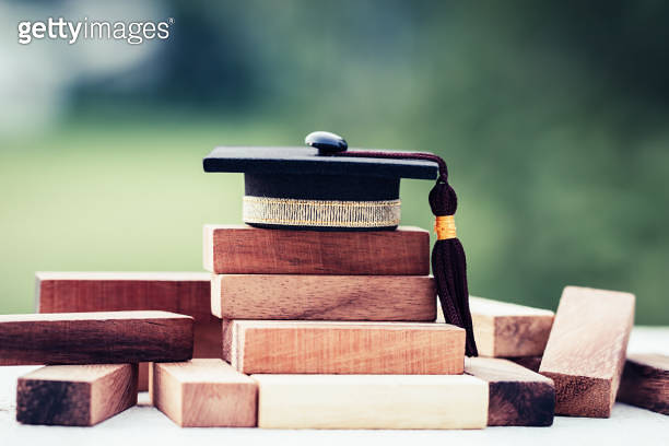 Graduation celebrating cap on wooden square blocks tower. Blank space ...