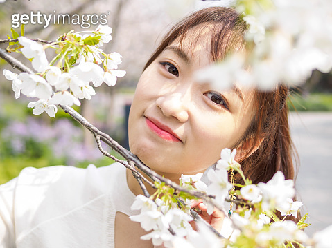 Outdoor portrait of beautiful young Chinese girl smiling among blossom ...