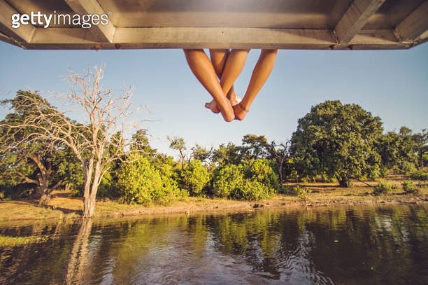 Foot Riding Away Couple Playing footsie feet hanging off safari boat (957312586) - 게티이미지뱅크