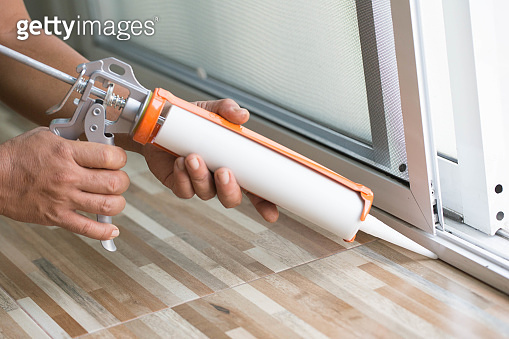 Window Connection Glue Men's hand uses silicone adhesive with a glue gun to repair worn ...