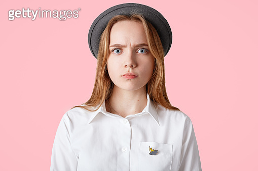 Candid shot of grumpy sad serious female wears elegant black hat and ...