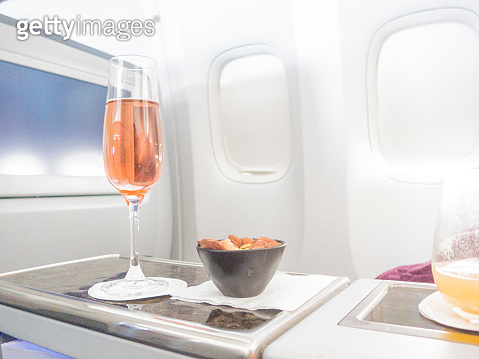 First Class Pink pink champagne and heated nuts in business class cabin, in flight ...
