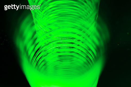 Green metal spiral / coil spring with blurred background on black ...