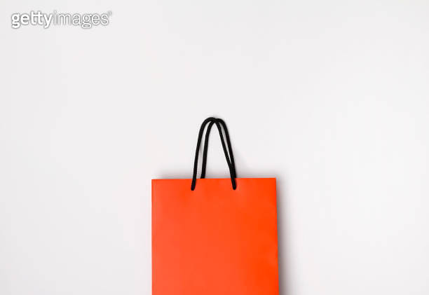 Orange paper shopping bag with black handles on the white background ...