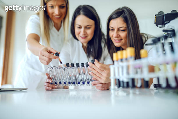 Three dedicated beautiful smiling caucasian female lab assistants ...