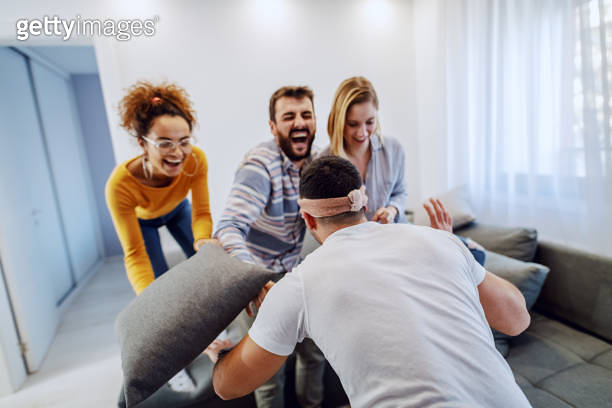 Group of cheerful friends having party at home.They are playing blind ...