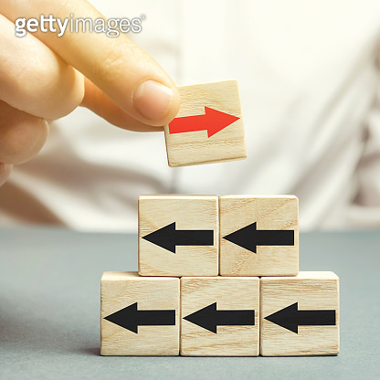 A man holds a wooden block with red arrow facing the opposite direction ...