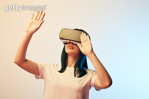 young woman wearing virtual reality headset and gesturing on beige and ...