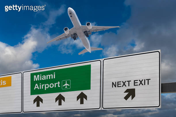 Road sign indicating the direction of Miami airport and a plane that ...