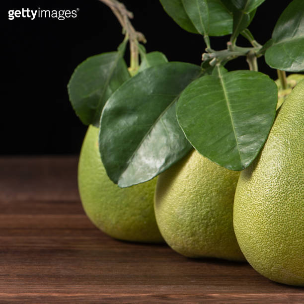 Fresh peeled pomelo, grapefruit, shaddock with green leaves on dark