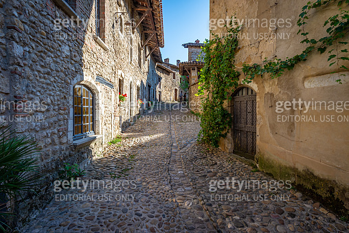 Tourists walking on a cobblestone street of the medieval town, Perouges ...