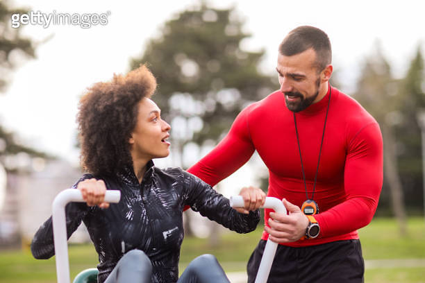 Buff fitness trainer encouraging an athletic woman as she's working out ...