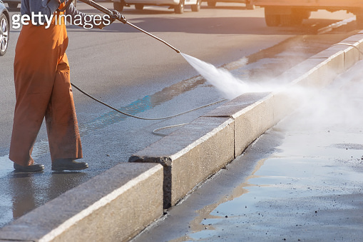 Worker cleaning driveway with gasoline high pressure washer splashing ...