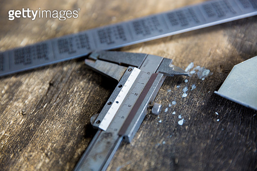 Vernier caliper and metal meter ruler on oil stained table, measuring ...