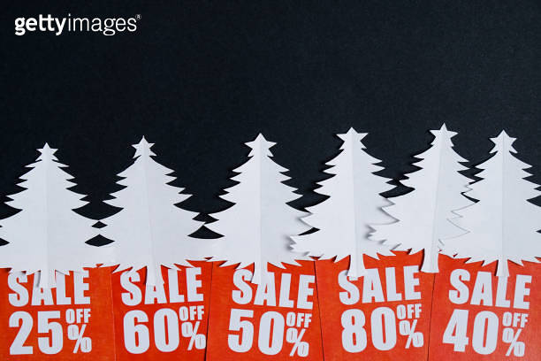 Paper Christmas trees with red discount cards on a black paper whatman ...