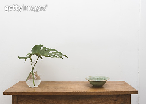 Monstera leaves in glass vase and green bowl on oak table 이미지 ...