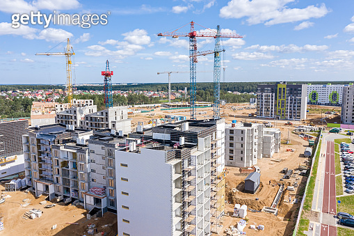 aerial view of newly built apartment buildings and cranes against blue ...