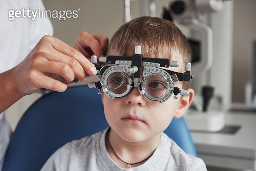 Eye Testing Boy Little boy with phoropter having testing his eyes in the doctor's ...